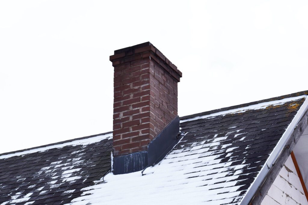 Light snow accumulating on a rooftop near the chimney