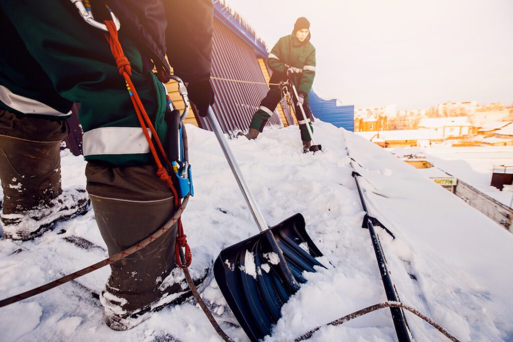Team of men working on removing heavy snow from a rooftop
